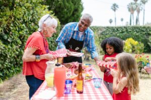 A joyful family gathers outdoors for a picnic, enjoying food and togetherness.