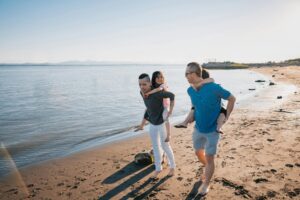 Legacy planning for nontraditional families. Two parents with children enjoying a sunny day during a beach walk.