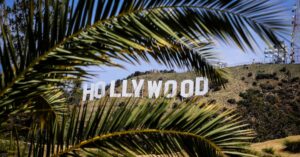 Famous Hollywood Sign framed by palm leaves on a sunny day in Los Angeles, California.