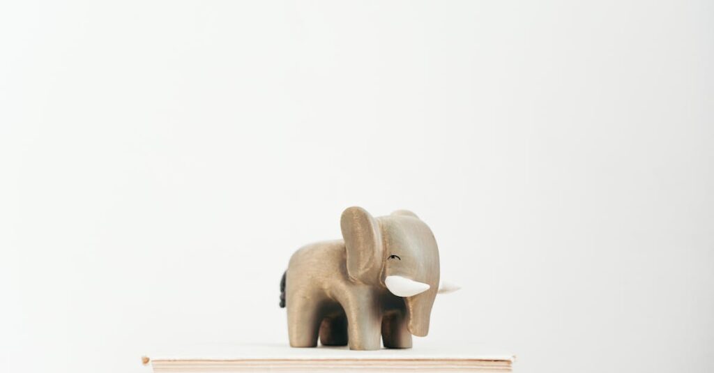 A minimalist scene with a wooden elephant figurine placed on top of stacked books against a light background.