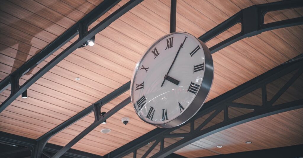 A large vintage-style clock with Roman numerals hanging indoors with modern architecture.